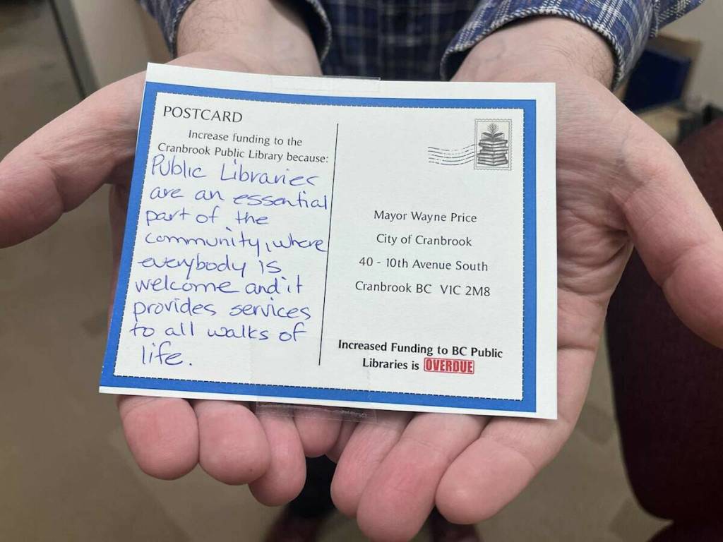 Mike Selby holds a postcard written to Cranbrook mayor Wayne Price, in support of library services (Gillian Francis/CranbrookTownsman)